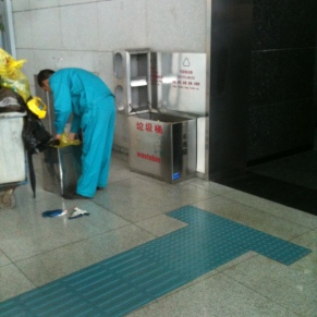 Qingdao Airport Maintenance Worker: completing his dirty deed. The trash and recycling are not supposed to mix!